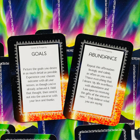 Affirmacijos kortelės: artimas planas dviejų variantų 'Goals' ir 'Abundance' su juodu rėmu ir spalvotu auroros fono dizainu