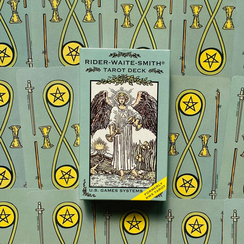 Tarot kortos Rider‑Waite‑Smith mintinės dėžutėje, centrinis viršaus kadras ant derančių kortų nugarėlių