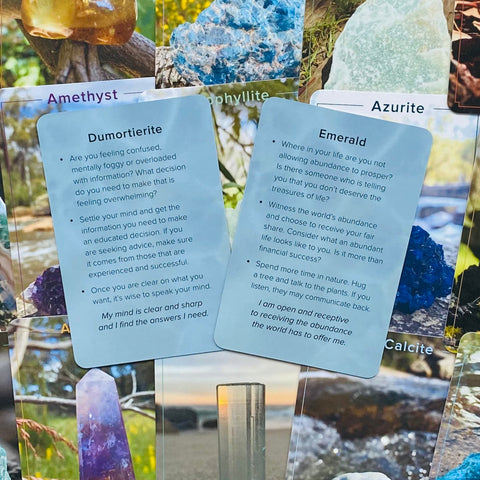 Kryštalų kortelės Dumortierite ir Emerald, mėlyni aprašymai su afirmacijomis, išdėstytos ant įvairių mineralų iliustracijų