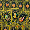 Tarot kortos juodu fonu su auksiniu ornamentu, trys atverstos kortos centre (Nine of Cups, Ten of Cups, Page of Cups)
