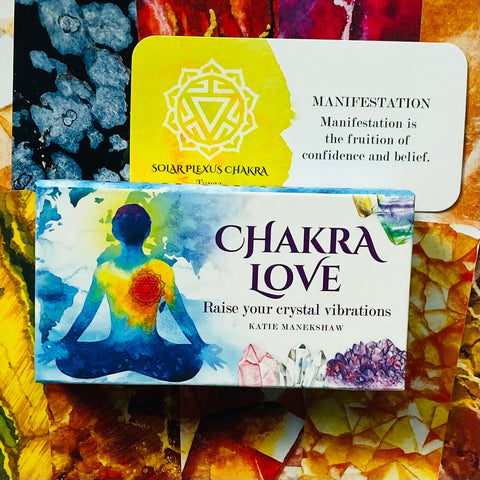 Chakra Love kortų rinkinys su akvareline meditacijos figūra ir matoma saulės rezginio kortele, užrašytu „Manifestation“ teiginiu