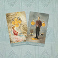 Tarot kortos – atviri „Five of Pentacles“ ir „Four of Pentacles“ kortų priekiniai dizainai ant šviesiai mėlyno fono, skirti detalėms įvertinti
