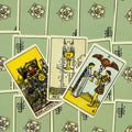 Tarot kortos Rider–Waite stiliaus, trys atviri kortai (Karalius monetų, Taurės tūzas, Taurių dvi) ant žalių nugarėlių