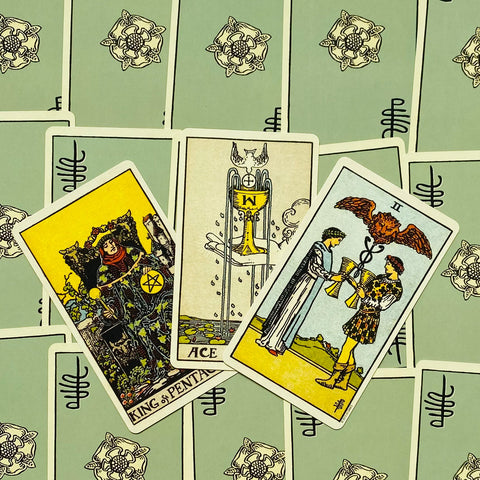 Tarot kortos Rider–Waite stiliaus, trys atviri kortai (Karalius monetų, Taurės tūzas, Taurių dvi) ant žalių nugarėlių