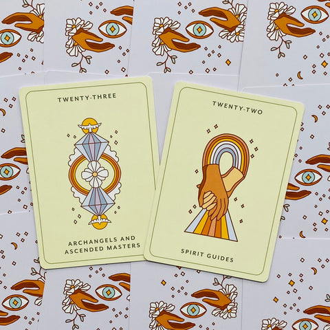 Kortų rinkinys: dvi atverstos orakulų kortos (Archangels ir Spirit Guides) ant gelsvo fono, plokščiai išdėstytos su dekoruotomis nugarėlėmis