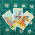 Tarot kortos Rider Waite: trijų Taurų išklotinė su Karalienės, Riterio ir Berniuko kortomis ant žalios ornamentuotos nugarėlės