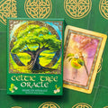 Celtic Tree Oracle kortų rinkinys — žalias dėklas su išraiškingu medžio piešiniu ir atversta Quert Apple korta, pakuotės priekinis vaizdas