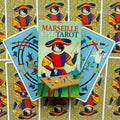 Marseille Cat Tarot taro rinkinys, spalvinga dėžutė centre su dviem atvertais kortomis ir ornamentinių nugarėlių fonu