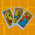 Tarot kortos Marseilio stiliaus – trys lazdų rūšies kortos (pusininkas, riteris, karalienė) ant geltono raštuoto fono