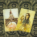 Tarot kortos Hush komplektas: dvi atvertos smėlio tonų kortos (X ir IX) su gėlių ir paukščio motyvais ant juodų nugarėlių