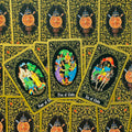 Tarot kortos juodo su aukso raštu nugarėmis, trys detalios figūrinės kortos (Four, Five, Six of Clubs) matomos