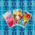 tarot kortos mėlynais nugarėlėmis, trijų kortų išdėstymas iš viršaus su ryškiais, skirtingų iliustracijų priekiais