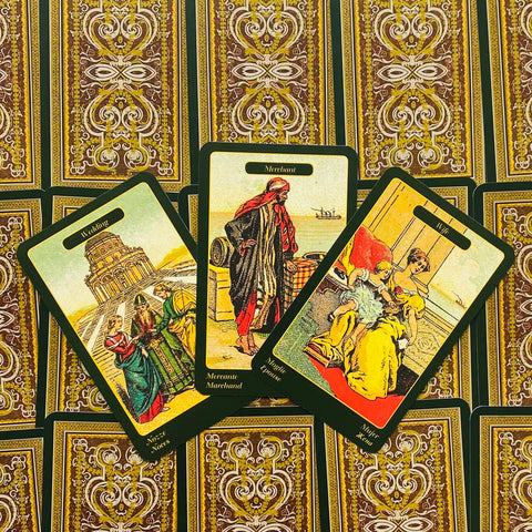 tarot kortos vintage žaliais kraštais, trijų kortų išdėstymas su išryškintu centre Merchant ir ornamentuotu kortų fone