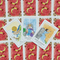 tarot kortos su raudonomis nugarėlėmis ir aiškiais iliustruotais paveikslais — Kardų karalius, Kardų karalienė ir Monetų tūzas matomi iš viršaus