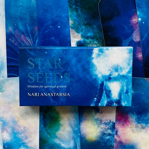 Kortos Star Seeds Nari Anastarsia, mėlyna kosminė pakuotė su eterinėmis iliustracijomis ir dalinai atvertais kortų nugarėlių motyvais