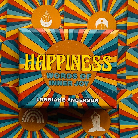 kortų rinkinys Happiness Lorriane Anderson – ryški saulės spindulių pakuotė centre, iš viršaus matomas ant sukrautų dėžių fono