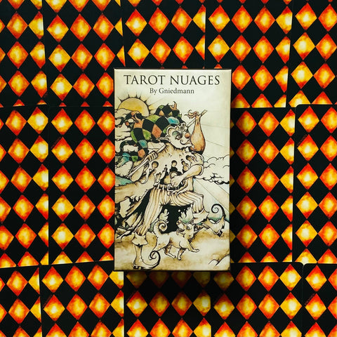 Tarot kortos Tarot Nuages by Gniedmann — dėžutė su iliustruotu viršeliu, atidengta ant karoškio raštuoto kortų fono