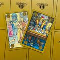 Tarot kortos Symbolon su auksiniu fonu, dvi atverstos spalvotos iliustruotos kortos matomos iš viršaus
