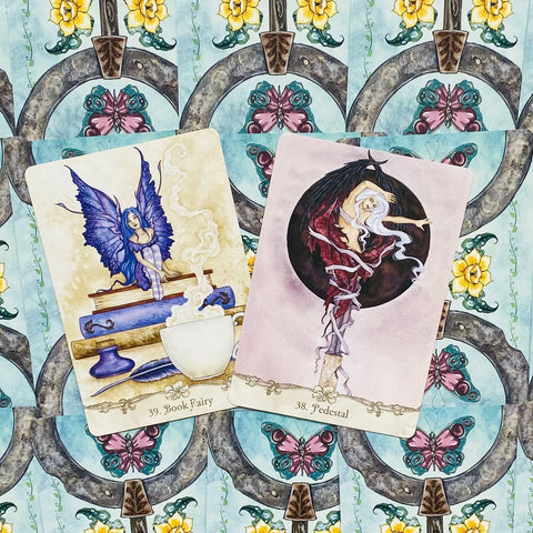 Orakulų kortos: Book Fairy su mėlyna fėja ir Pedestal su rožine figūra ant drugelių rašto nugarėlių