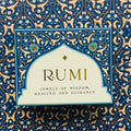 Rumi kortų rinkinys su mėlynais ir aukso ornamentais ant priekinio dangtelio, centrinis dizaino priartinimas