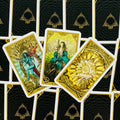 Tarot kortos su auksinėmis kraštinėmis, trys atverstos didžiųjų arkanių kortos (Pasaulis, Teismas, Saulė) ant juodų nugarėlių