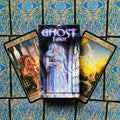Ghost Tarot kortų rinkinys dėžutėje su vaiduokliškomis iliustracijomis, kortos išskleistos ant mėlyno ir aukso rašto