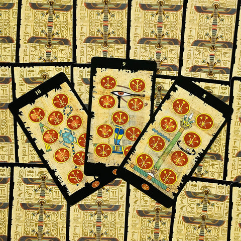 Tarot kortos egiptietiško dizaino, viršaus fotografija su trimis monetų rūšies kortomis (8, 9, 10) ir juodais kraštais