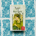 Tarot kortos dėžutė Tarot of the Old Path su žalia karalienės iliustracija ir matomu raudonu AGM logotipu, priekis