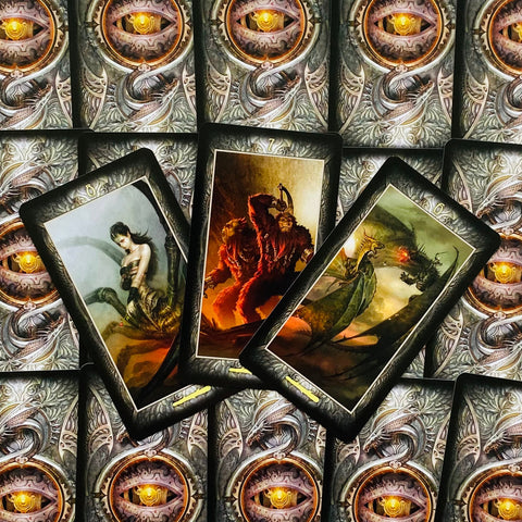Tarot kortos su tamsiomis dekoruotomis nugarėlėmis, trys atverstos kortos kampu rodo fantazines figūras ir drakonus
