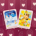 tarot kortos rožiniais rėmeliais — dvi atviros kortos (Emotional Freedom ir The Divine Masculine) ant bordo fono, aiškios iliustracijos