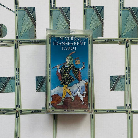 tarot kortos Universal Transparent stikliniame dėkle, stačiai nufotografuotos ant ornamentuoto balto fono, matomas mėlynas viršelis