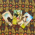 Tarot kortos — trys Pentaklių kortos (Page, Knight, 10) ant raštuoto bordo‑auksinio fono, kampu išdėstytos
