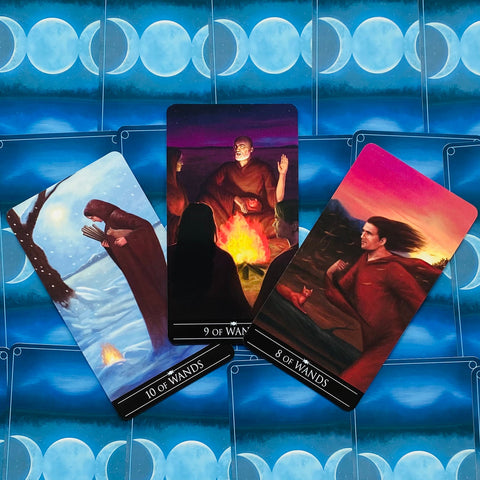 Tarot kortos atverstos 8, 9 ir 10 lazdelės; centre 9 prie laužo, kairėje sniege 10, dešinėje saulėlydyje 8