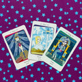Tarot kortos fanuotos trimis pasirinktomis kortomis ant violetinio žvaigždėto audinio, pabrėžia kortų iliustracijas