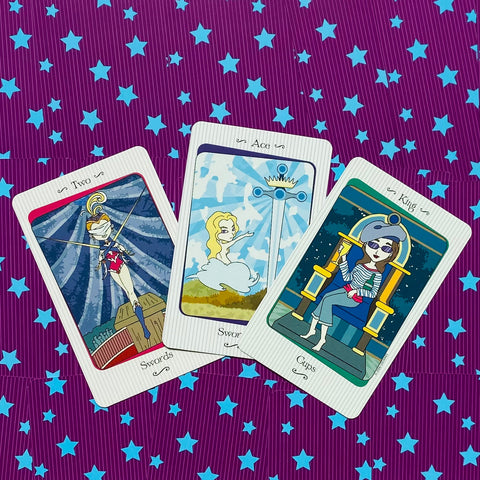 Tarot kortos fanuotos trimis pasirinktomis kortomis ant violetinio žvaigždėto audinio, pabrėžia kortų iliustracijas