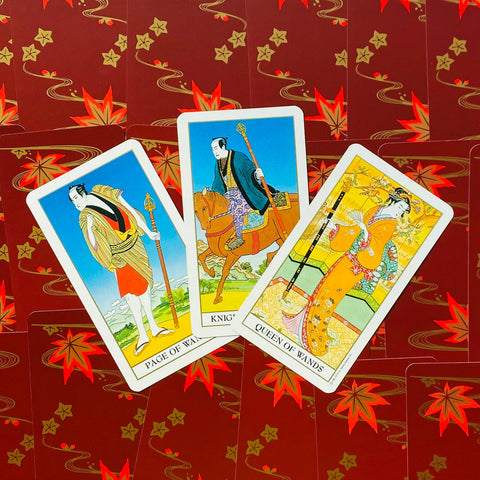 Tarot kortos japoniško dizaino, trys atvertos Lazdų kortos (Puslapis, Riteris, Karalienė) iš viršaus ant raudonų nugarėlių