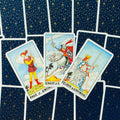 Tarot kortos Rider–Waite stiliaus, trys kardų rūmų kortos (Page, Knight, Queen) priekiniu kampu ant tamsios žvaigždėtos nugarėlės