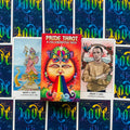 Pride Tarot kortų rinkinys su ryškia vaivorykšte dėkle, pažymėtas uždaru deniu ir atidengtomis Queen of Cups ir Knight of Cups kortomis