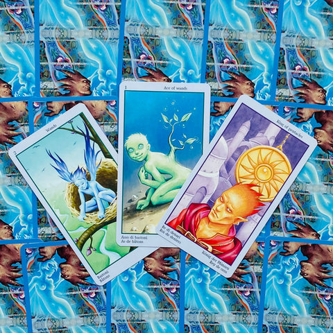 Tarot kortos skirtos skaitymui: trys atvertos spalvotos kortos (Asas lazdelės, 2 lazdelės, monetų karalius) ant mėlyno raštuoto fono