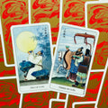 Tarot kortos su kinų stiliaus iliustracijomis — atverstos Two of Cups ir Three of Cups, artimas kampas ir raudonai auksinės nugarėlės