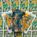 Crystal Tarot kortų dėžutė su Elisabetta Trevisan viršeliu, trys atvertos ryškios kortos ir ornamentinis fonas uždengtas kortomis