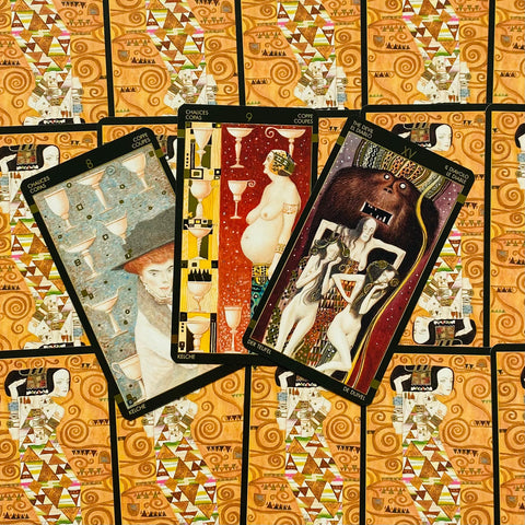 Tarot kortos su oranžinėmis ornamentuotomis nugarėlėmis, trys atverstos kortos su Velniu ir taurėmis, skirtos rinkinio demonstravimui