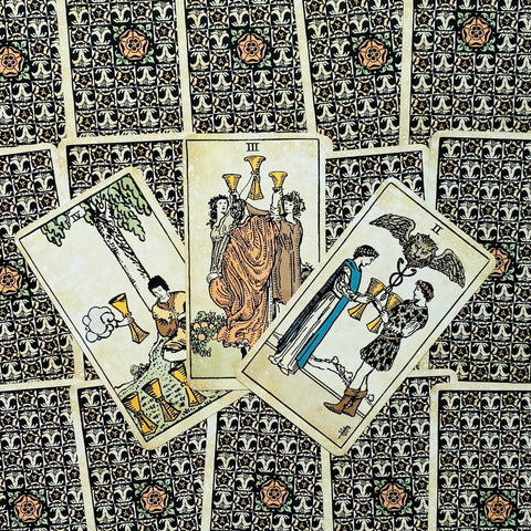 tarot kortos Rider–Waite stiliaus, sendintos smėlio spalvos priekinės kortos ir ornamentuotos nugarėlės, trijų taurų išdėstymas skaitymui