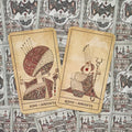 tarot kortos Serpents — kreminiai Karalius ir Karalienė, išdėstyti iš priekio ant ornamentuotos nugarėlės