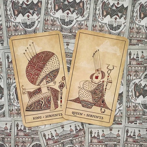 tarot kortos Serpents — kreminiai Karalius ir Karalienė, išdėstyti iš priekio ant ornamentuotos nugarėlės