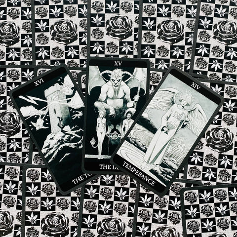tarot kortos juodai baltos, trys didžiosios arkanos (Bokštas, Velnio, Saikas) padėtos vėduoklės formoje ant rožių rašto