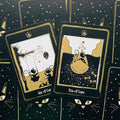 Tarot kortos juodos su auksinėmis detalėmis ir katinų iliustracijomis, dvi atidengtos kortos (Five ir Six of Cups) ant žvaigždėto fono