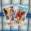 Tarot kortos su mėlynais nugarėlių raštais, atverstos Monetų karalienė ir Monetų riteris, dvi kortos parodytos iš arti