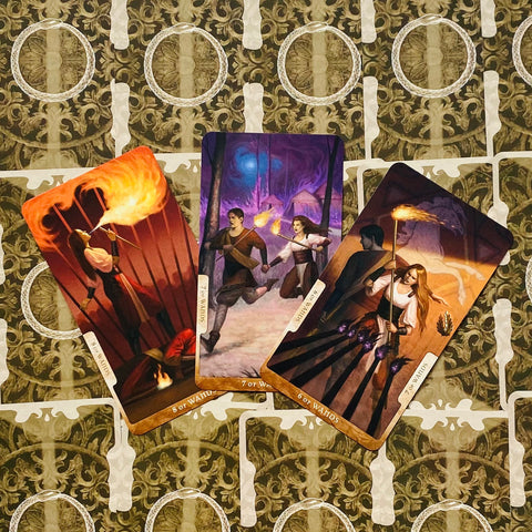 Tarot kortos — trys Lazdų kortos (6–8), šiltų liepsnų scenos ir ornamentinis fono raštas, apžvalgos kampas iš viršaus