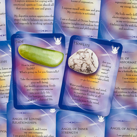 Orakulo kortos su kristalais – centrinės kortos rodo žalią jade kairėje ir baltą howlite dešinėje ant violetinio fono